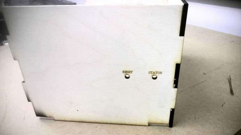 Single assembled box side showing the reset button hole and LED aperture