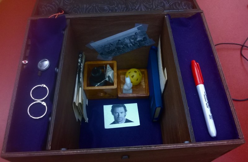 Open box interior showing collected mementos and photographs including Hugh Jackman