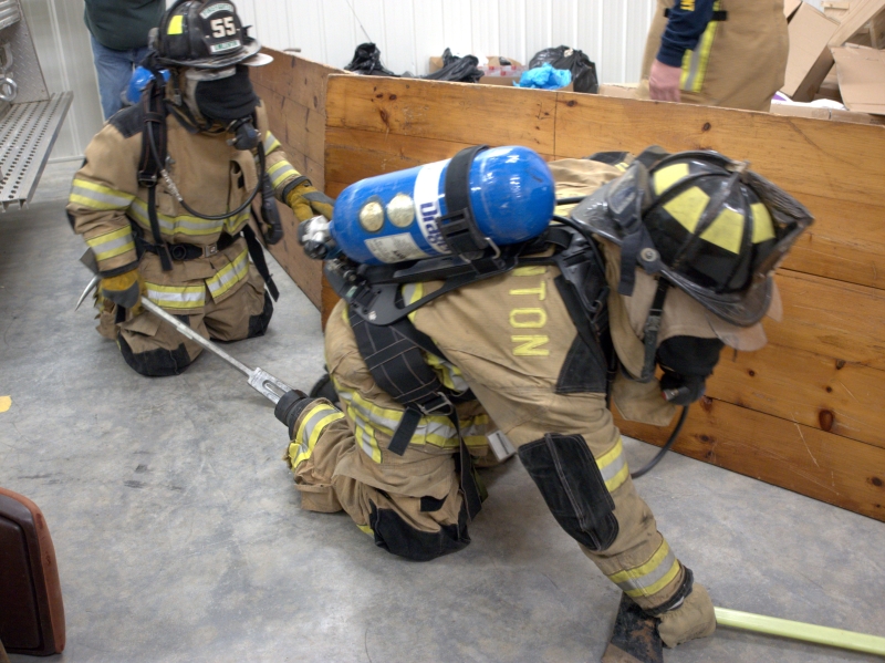 Two team members navigating a smoke maze during firefighter training at a fire station
