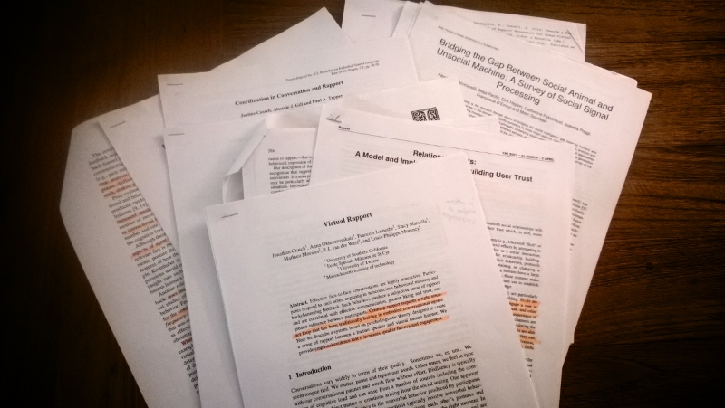 Stack of printed research papers with handwritten annotations about rapport indicators